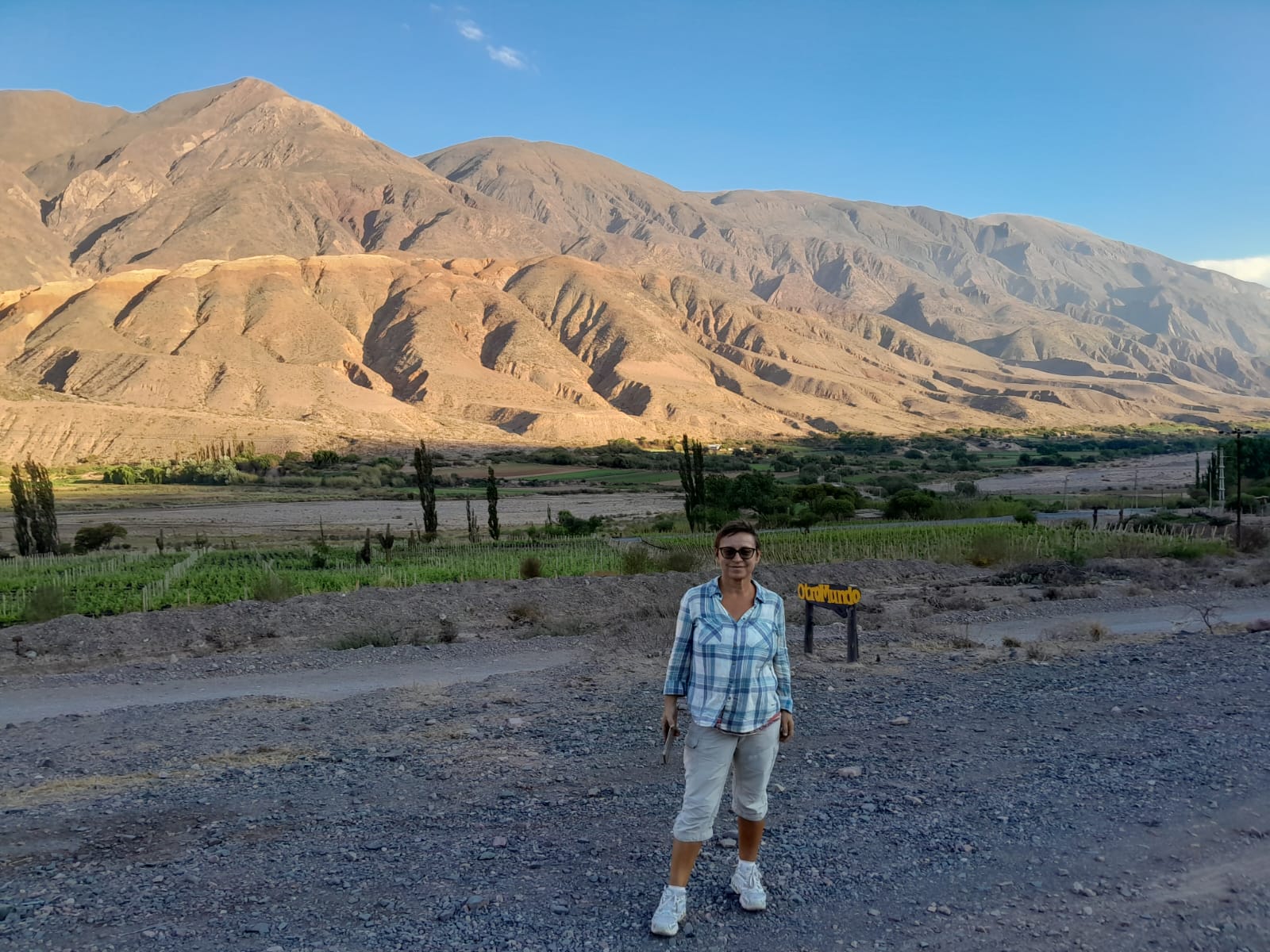 Mujer sentada sobre un tronco frente a una cascada doble en un bosque frondoso de Argentina.