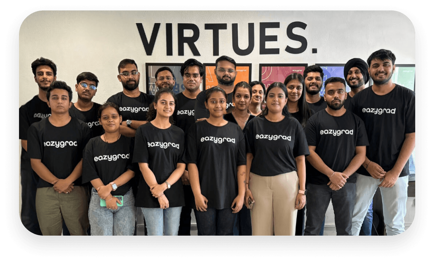 Group photo of individuals wearing black shirts, standing together in front of a "VIRTUES" wall sign.