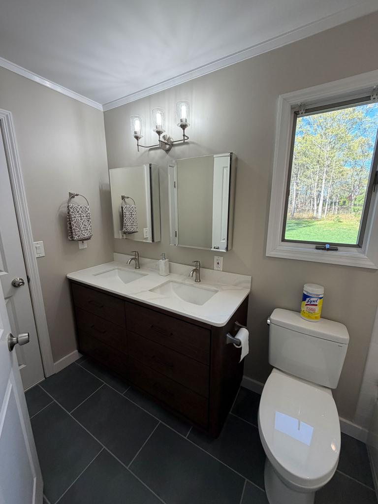 Renovated bathroom with a double vanity, framed mirrors and slate tile floor