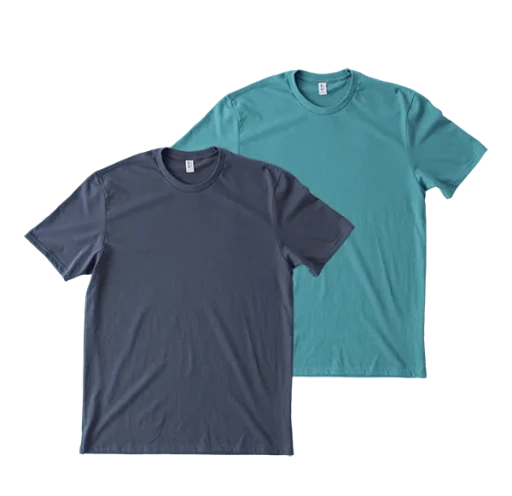 Two plain T-shirts, one in light pink and the other in dark blue, are layered flat on a surface, showcasing their simple round-neck design and soft, casual fabric.
