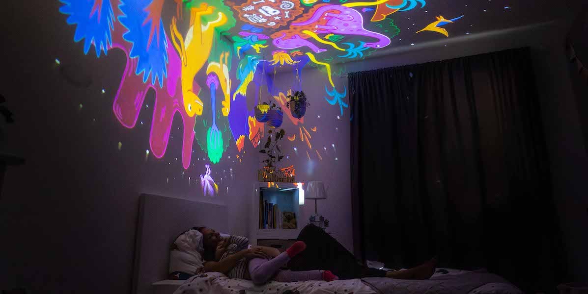 BiMA Magazine. Eine Mama und ihr Kind tauchen in eine bunte, immersive Bildwelt ein und erleben Fantasie und Abenteuer im Dinoland.