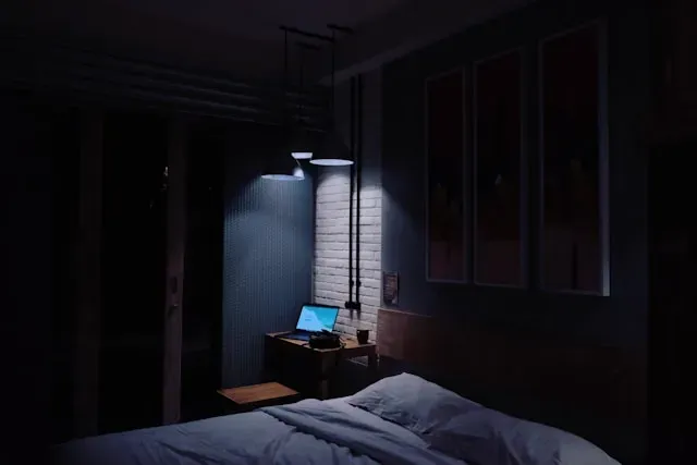 warm lam lightning a bedroom while a laptop shows a night mode sreen.