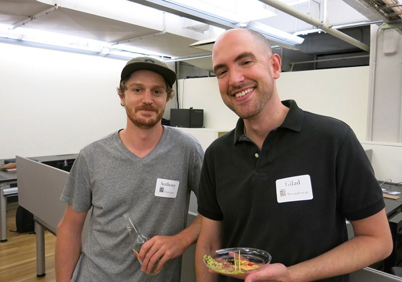 photo of two men, one is eating the other one is having a dring