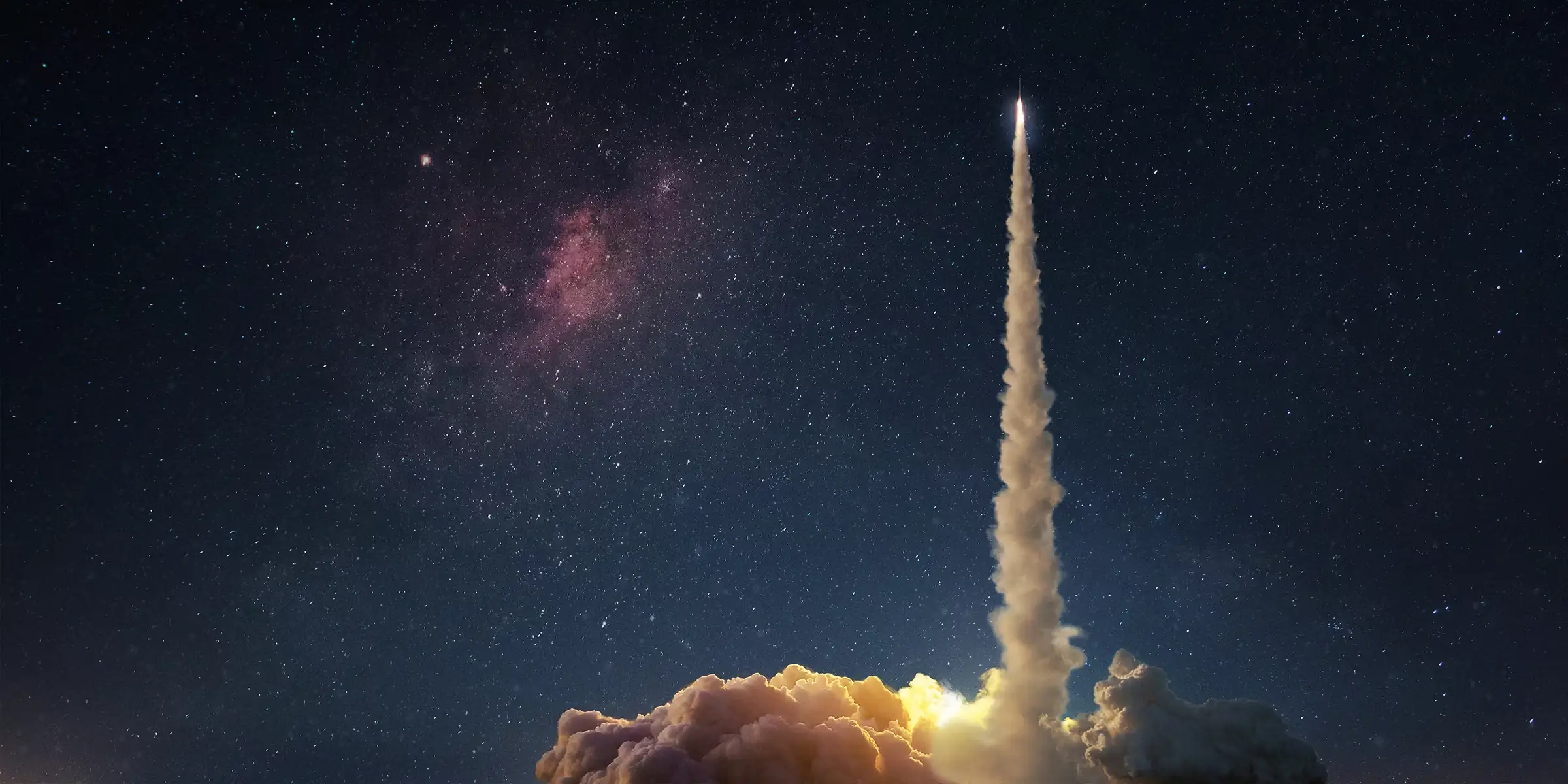 Rocket launching into a night sky, leaving a bright trail above clouds.
