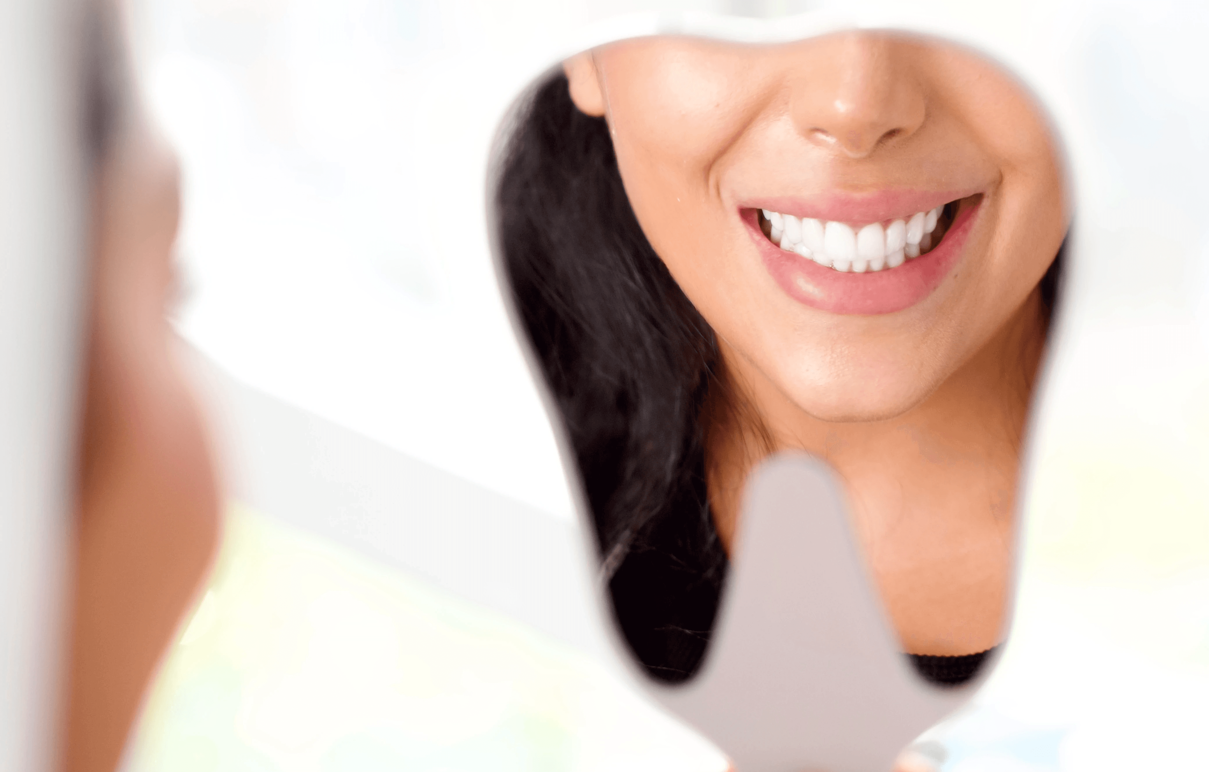 Smiling woman's reflection with white teeth in a dental mirror, indicating relief from Jaw Pain.