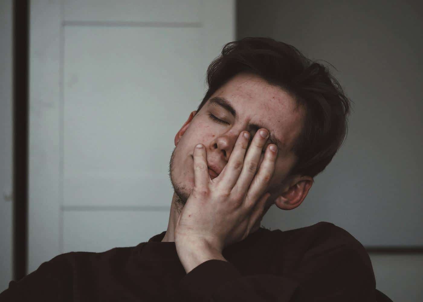 Signs of low testosterone - man holding his face in exhaustion