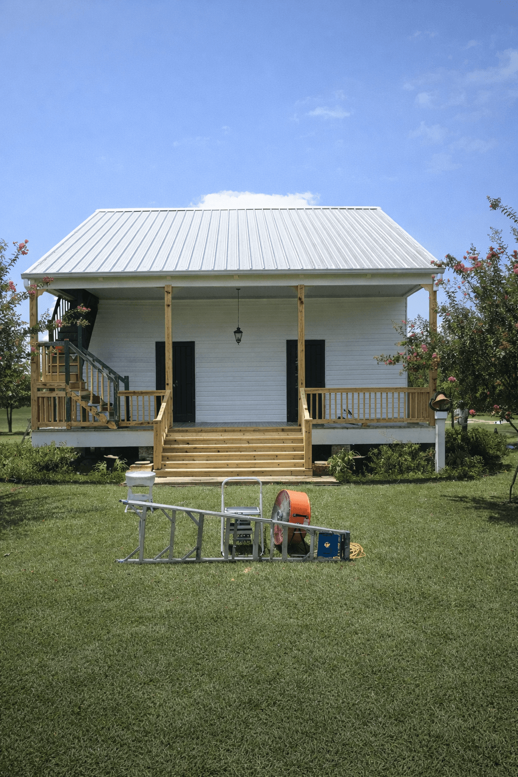 A modern, luxury beachfront villa with large glass windows and balconies overlooks a rocky shoreline, surrounded by palm trees at sunset.