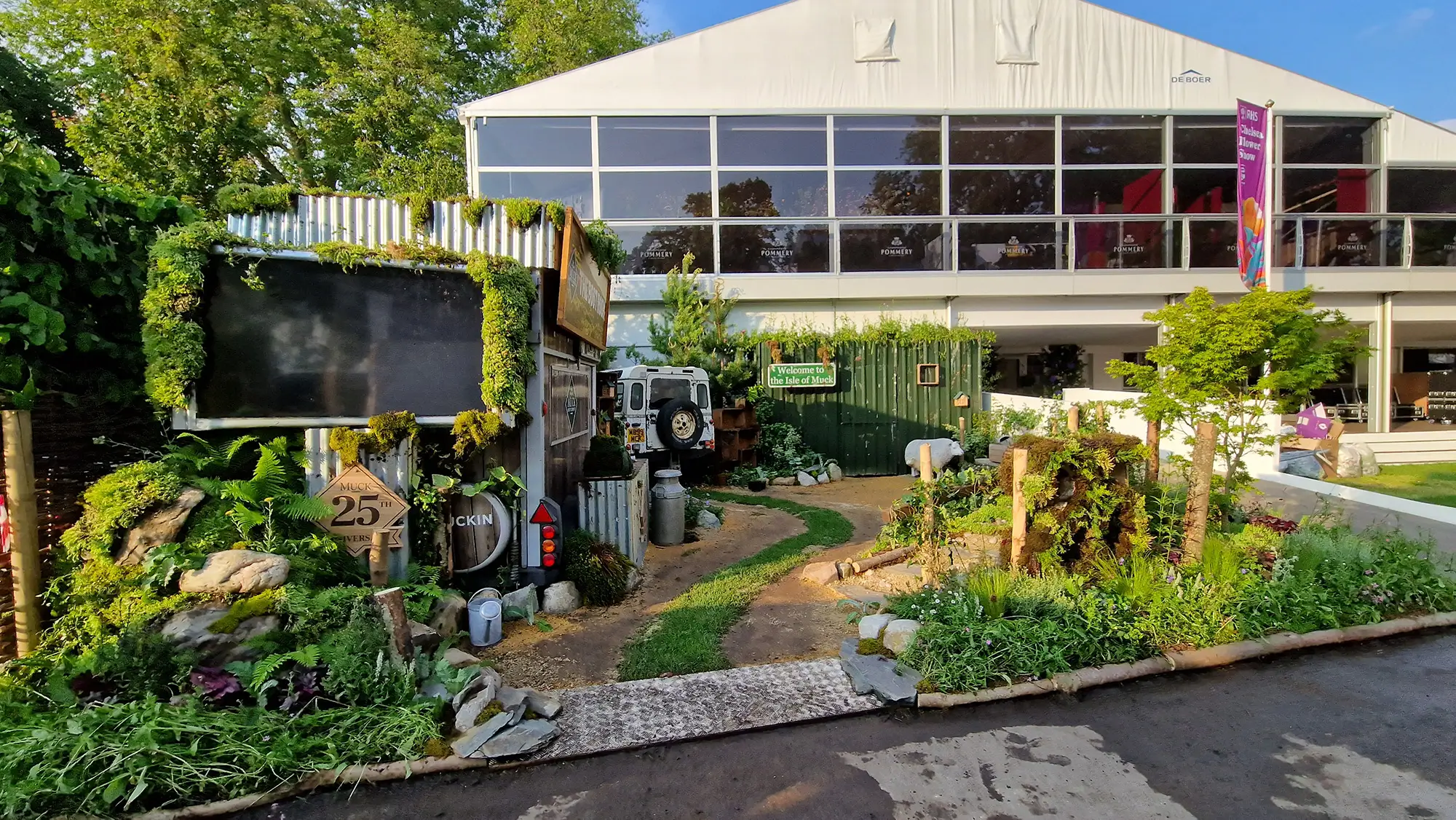 A landscaped garden in front of a modern building with large windows and greenery surrounding the pathway.