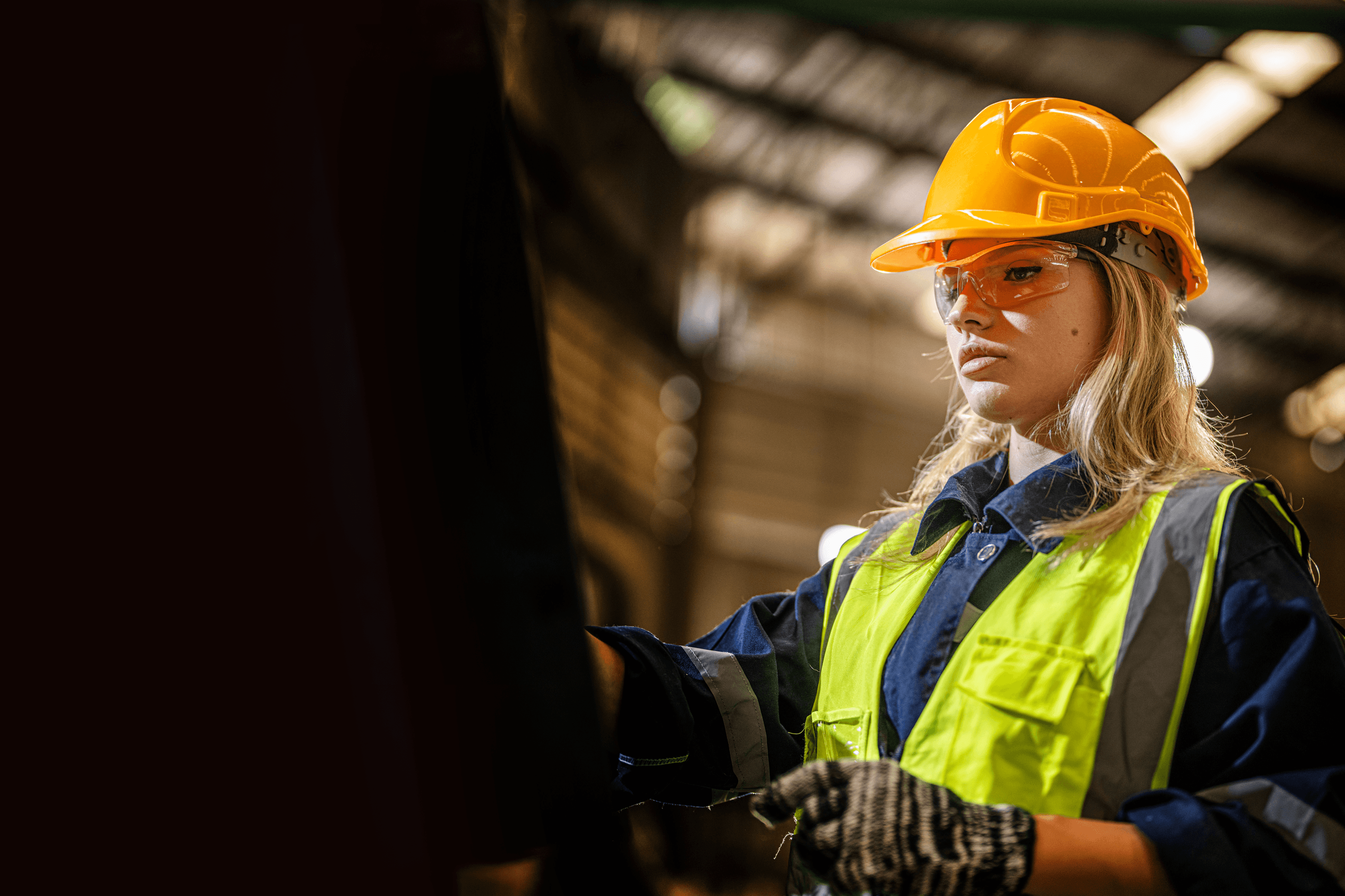 Mulher operária com capacete e colete fluorescente.