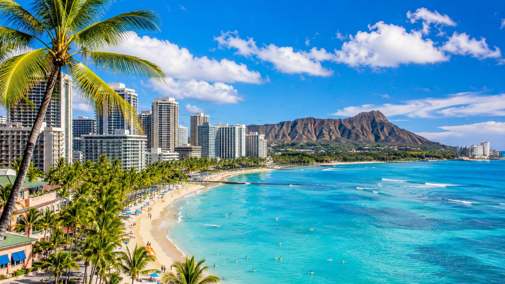 Honolulu coastline with beach, palm trees and ocean under a bright sky