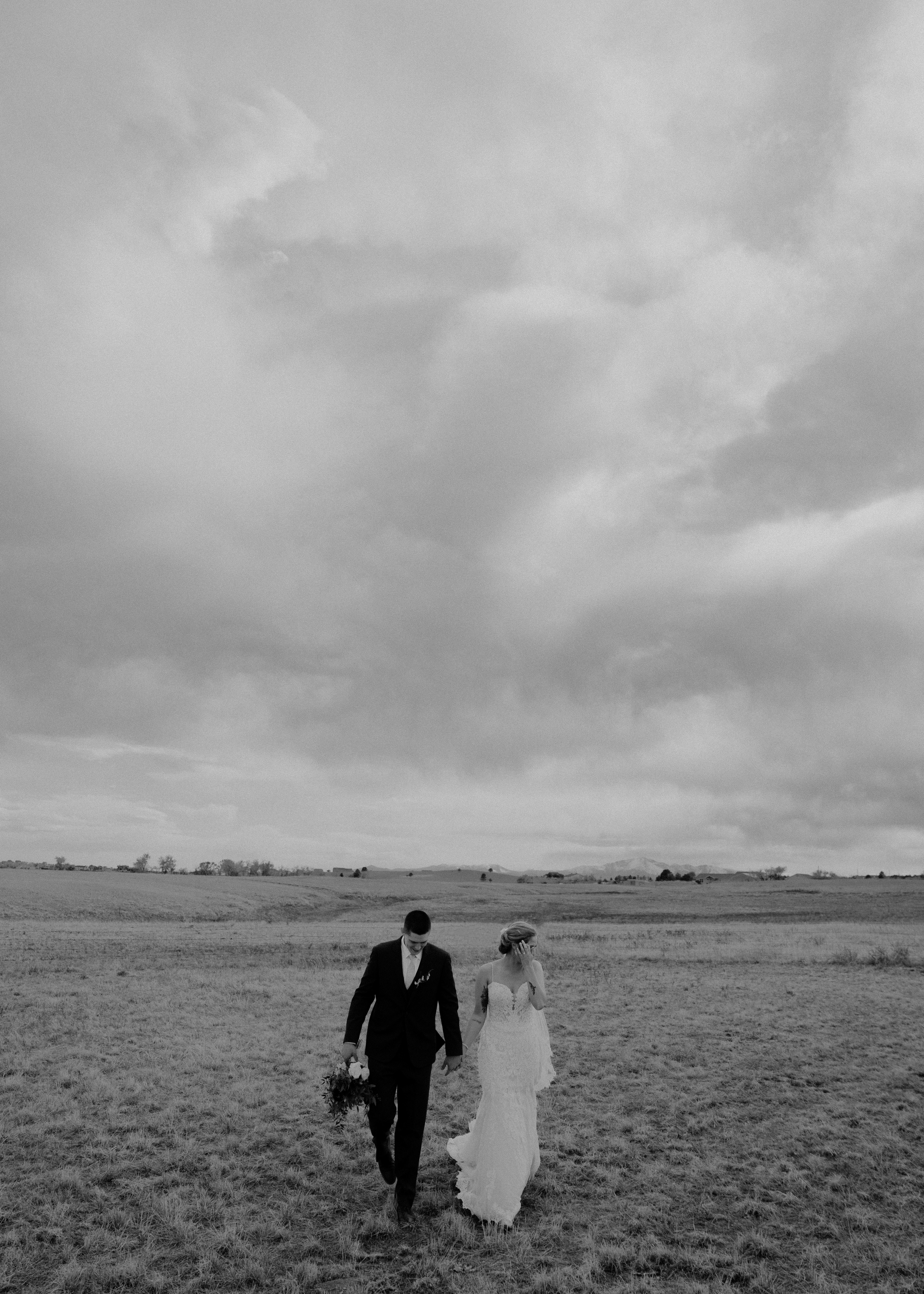 a bride and groom walking through a field