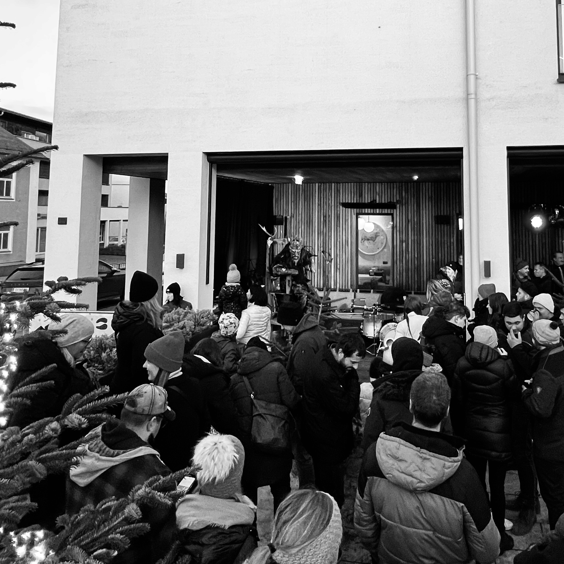 A crowd gathered outside a building listening to a speaker on a podium, captured in black and white.