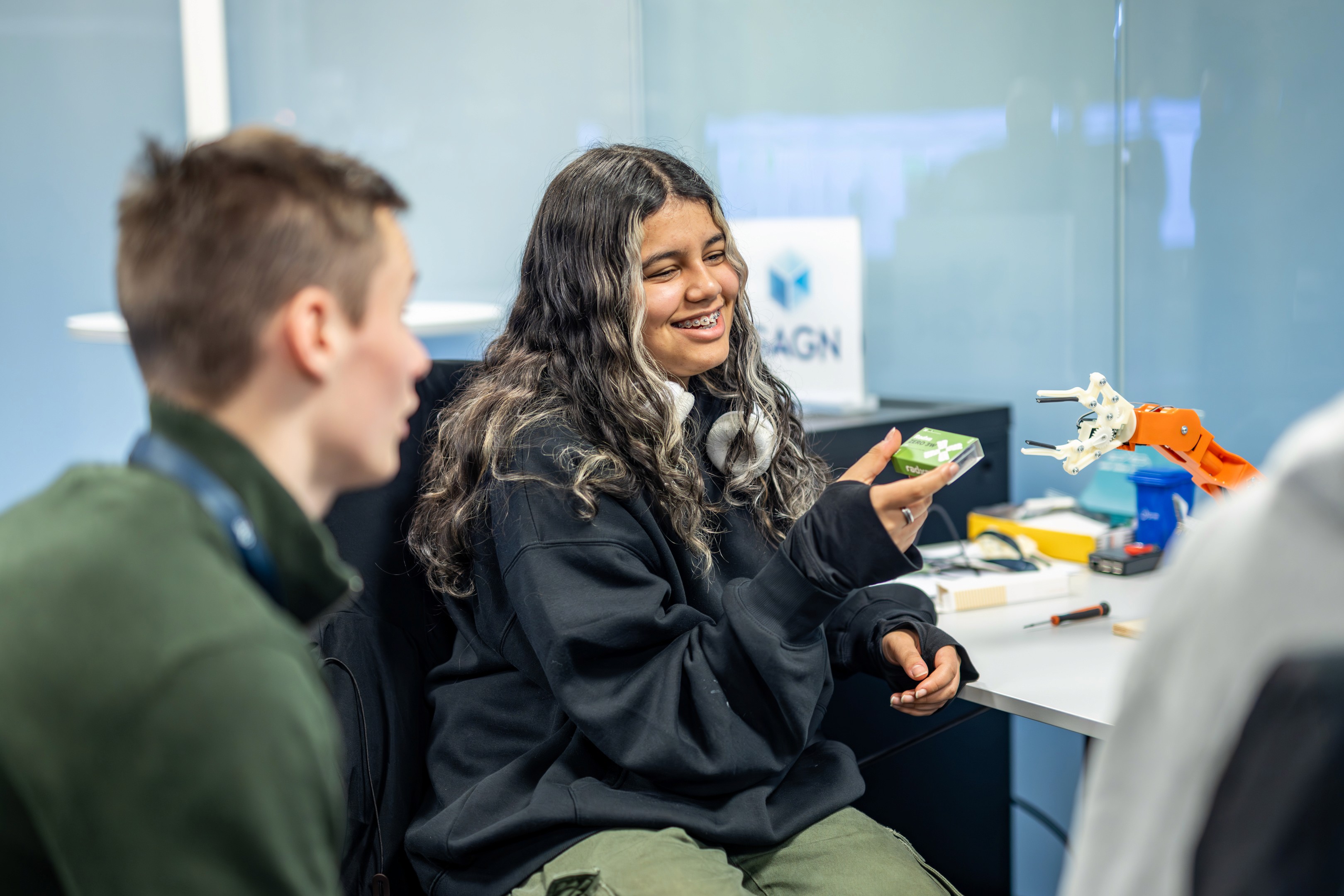 Two people are engaged in conversation, smiling and enjoying a moment together in a bright, casual setting.