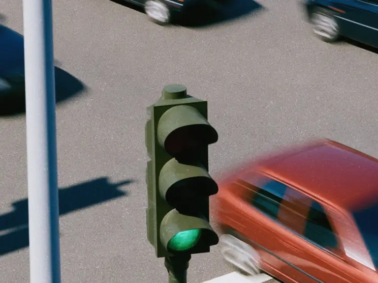 Green traffic light above cars moving through an intersection.
