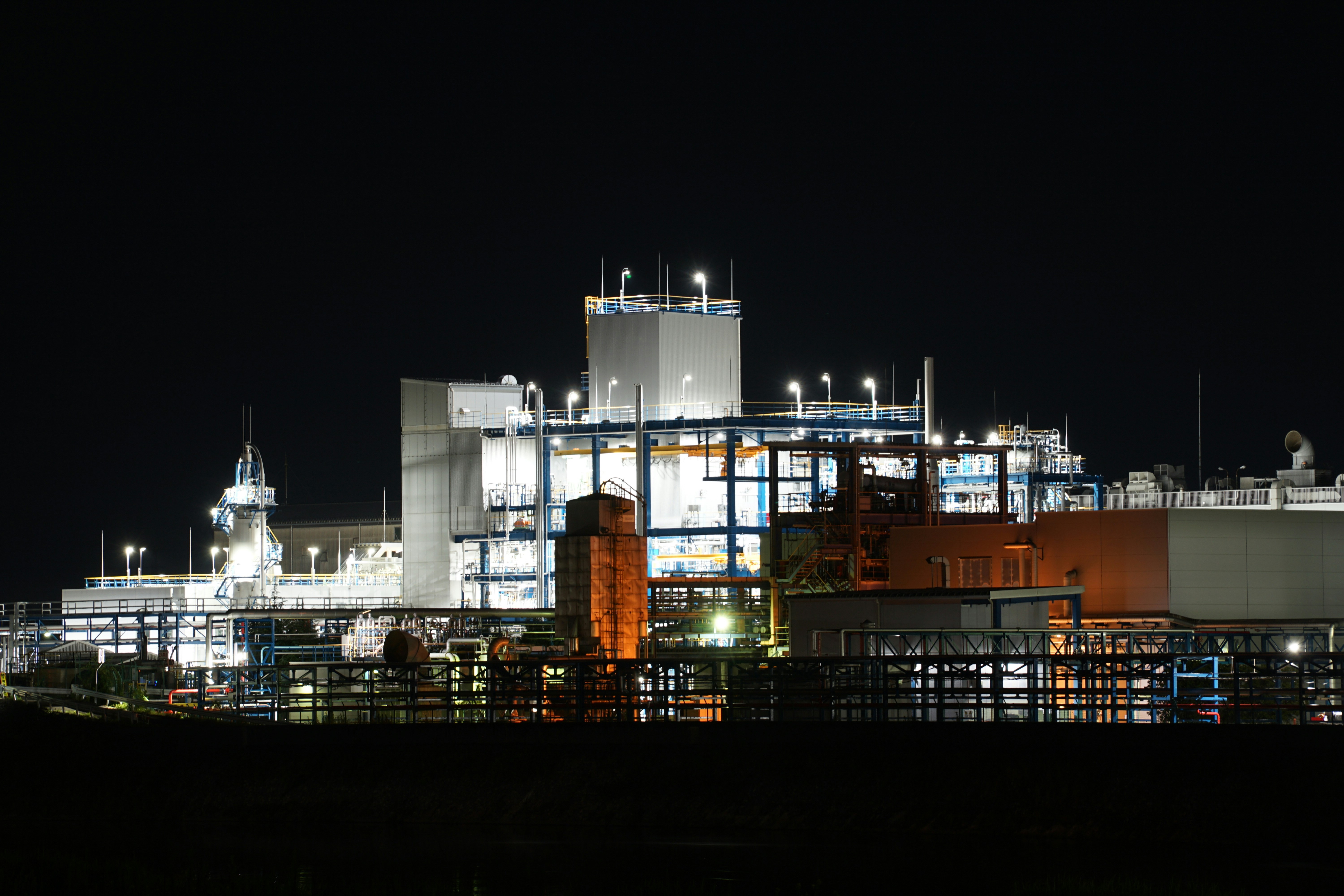 Industrial complex illuminated at night against dark sky