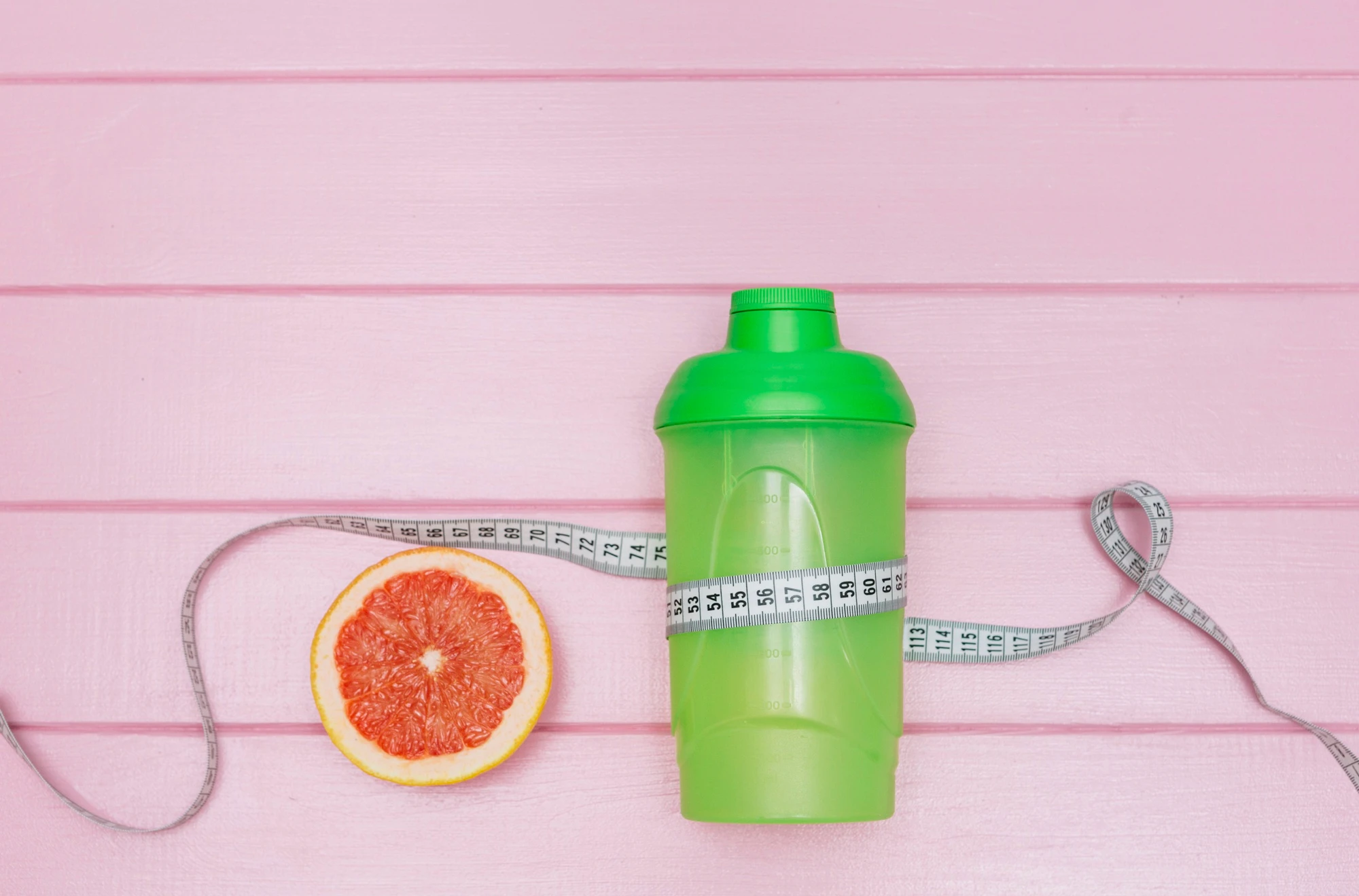 Sports water bottle and tape measure around a grapefruit, illustrating the benefits of hydration for weight loss