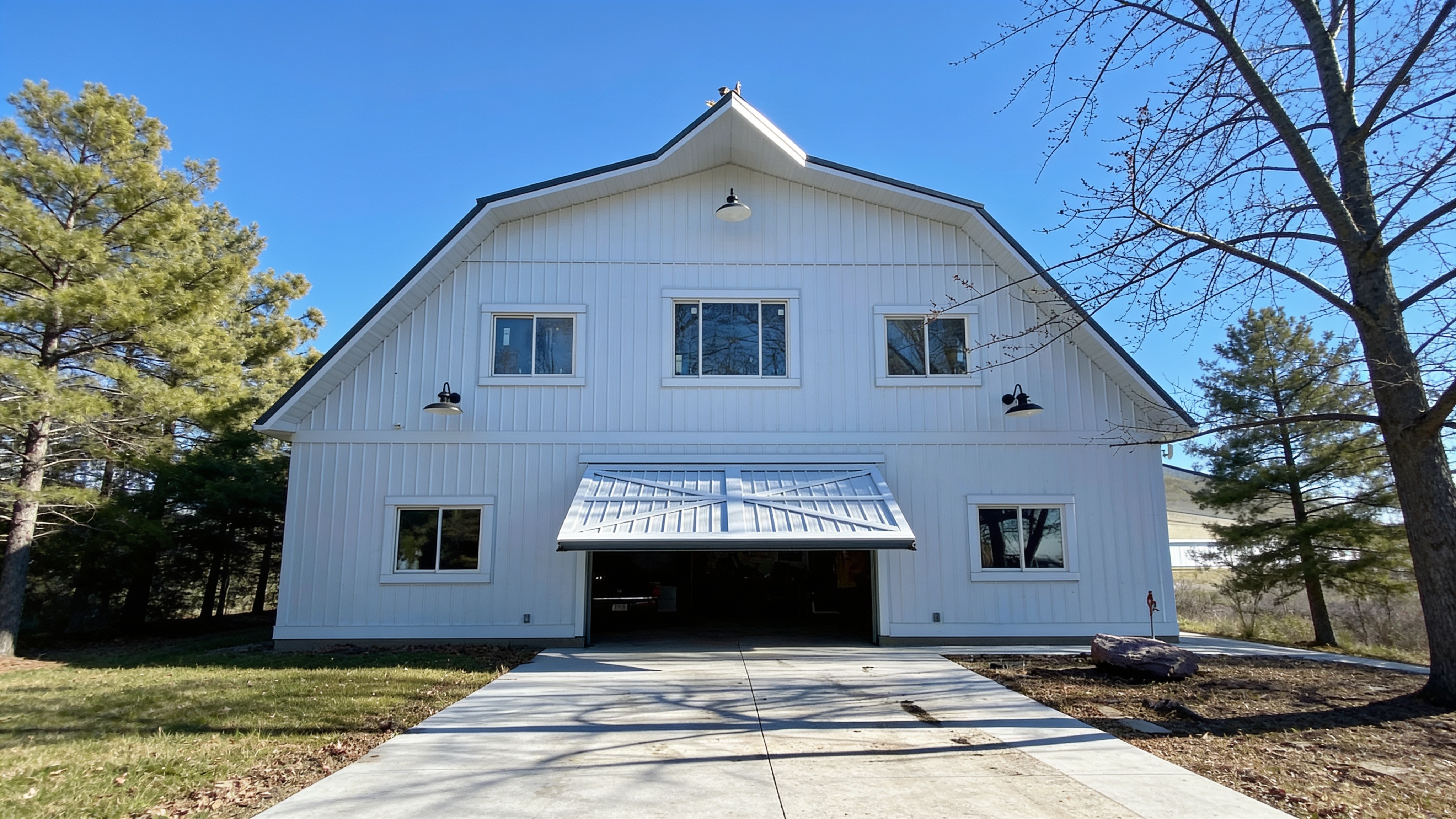 16-foot by 12-foot hydraulic agricultural door on a white barndominium, open in the awning position