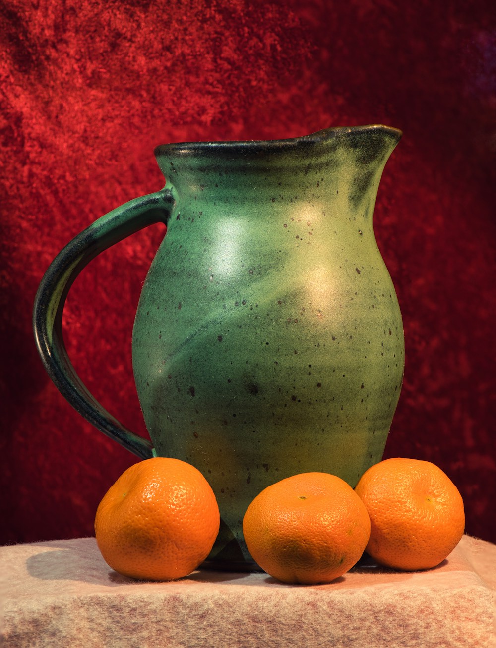 Green ceramic pitcher with oranges