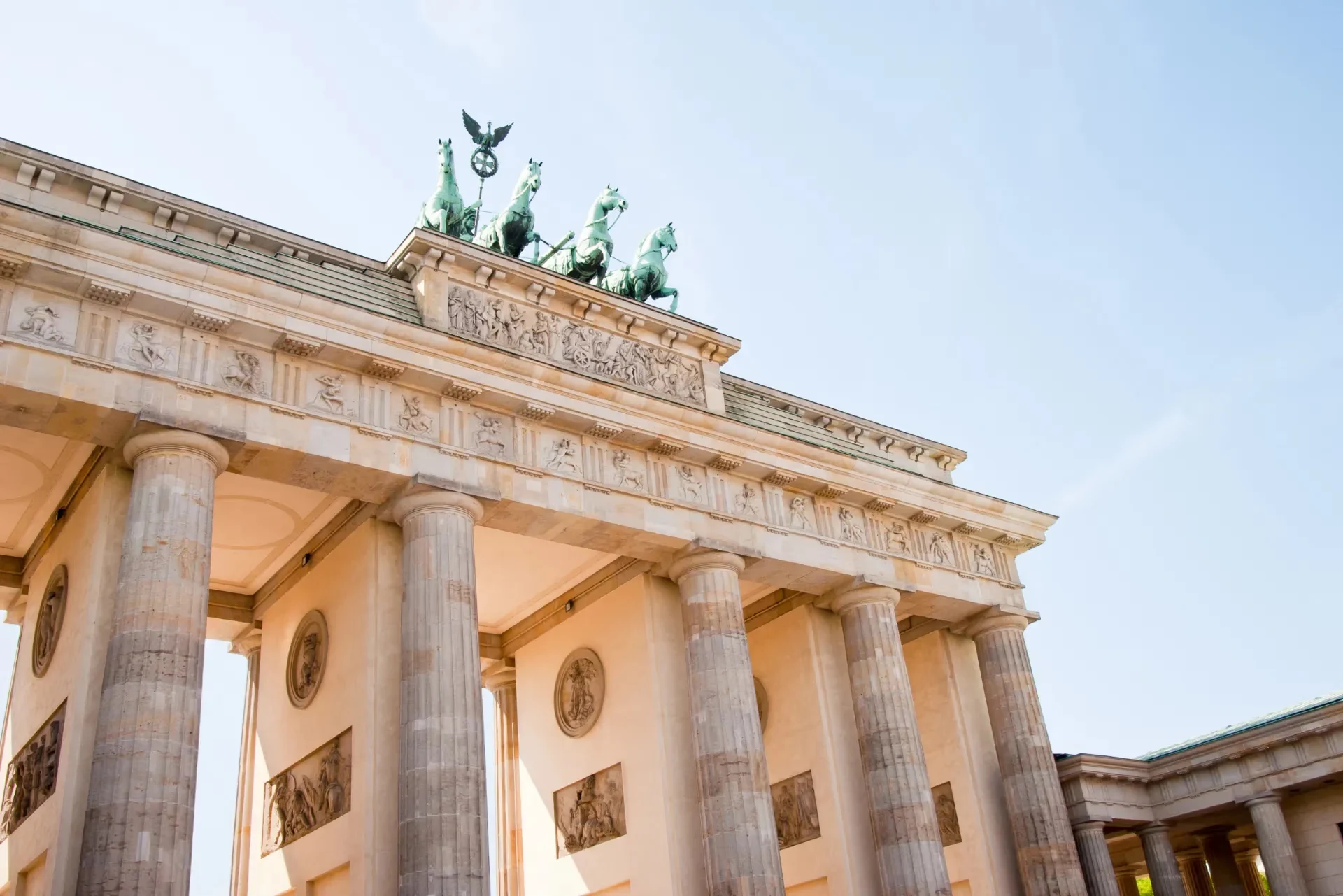 Nahaufnahme des Brandenburger Tors, die seine imposanten Säulen und die Quadriga auf der Spitze unter einem klaren blauen Himmel zeigt.