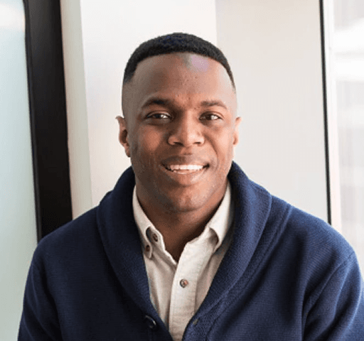 a man in a blue shirt smiling at the camera