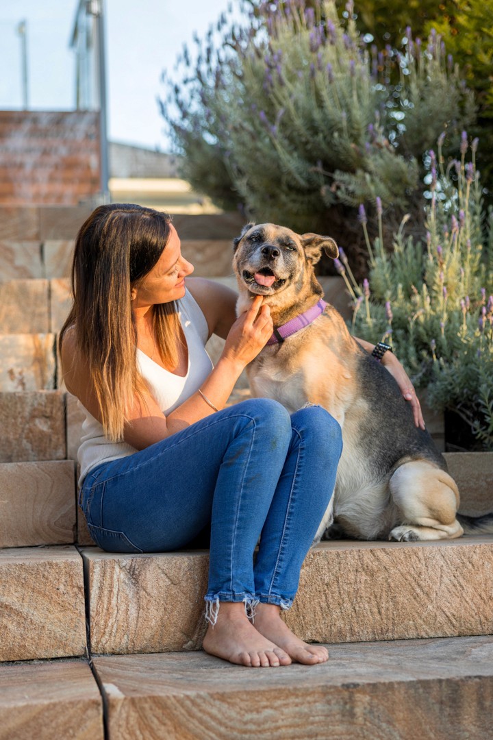 Woman sitting with her dog on sandstone stairs