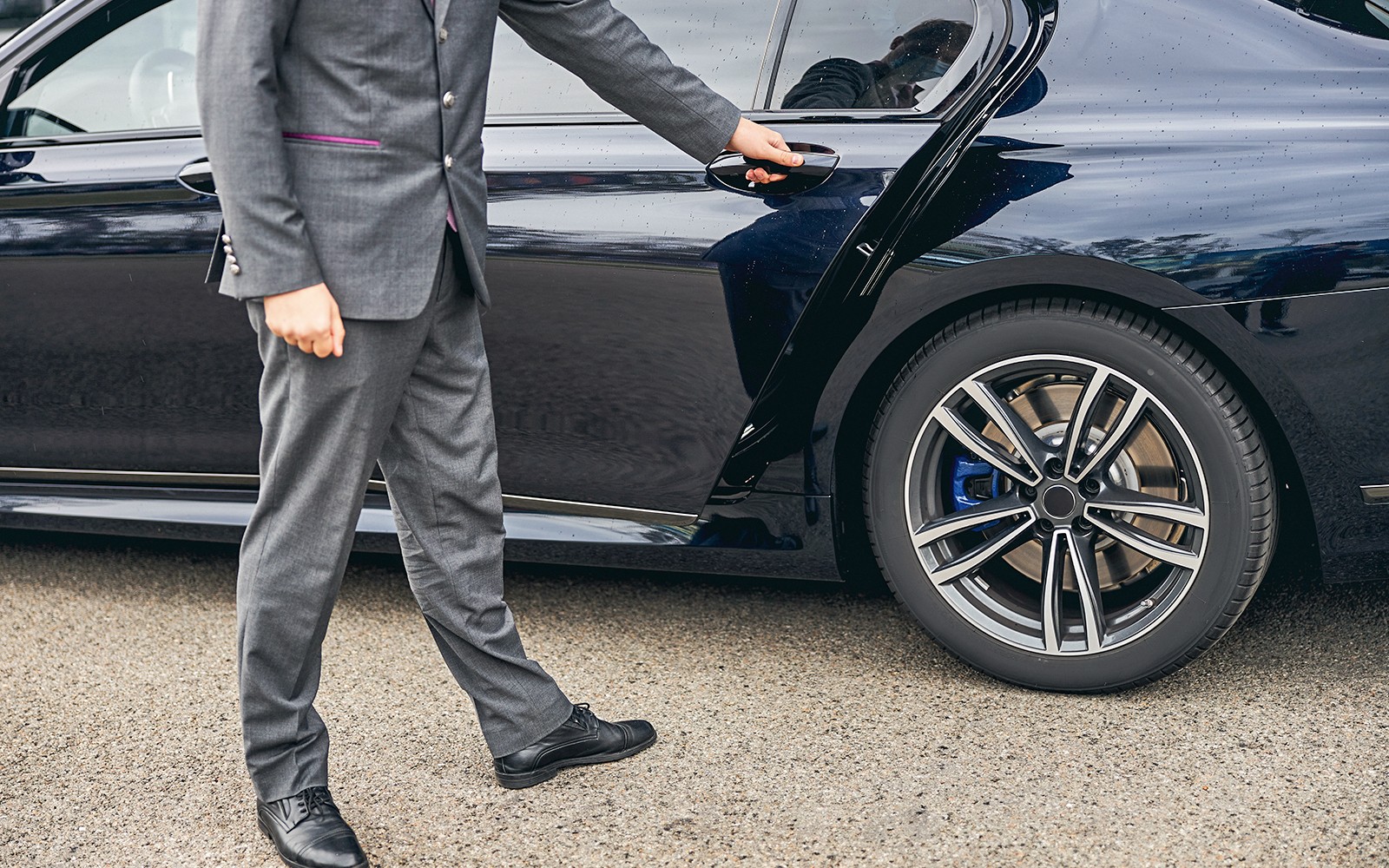 दुबई और अबू धाबी शटल सेवा के लिए ड्राइवर कार का दरवाजा खोल रहा है।