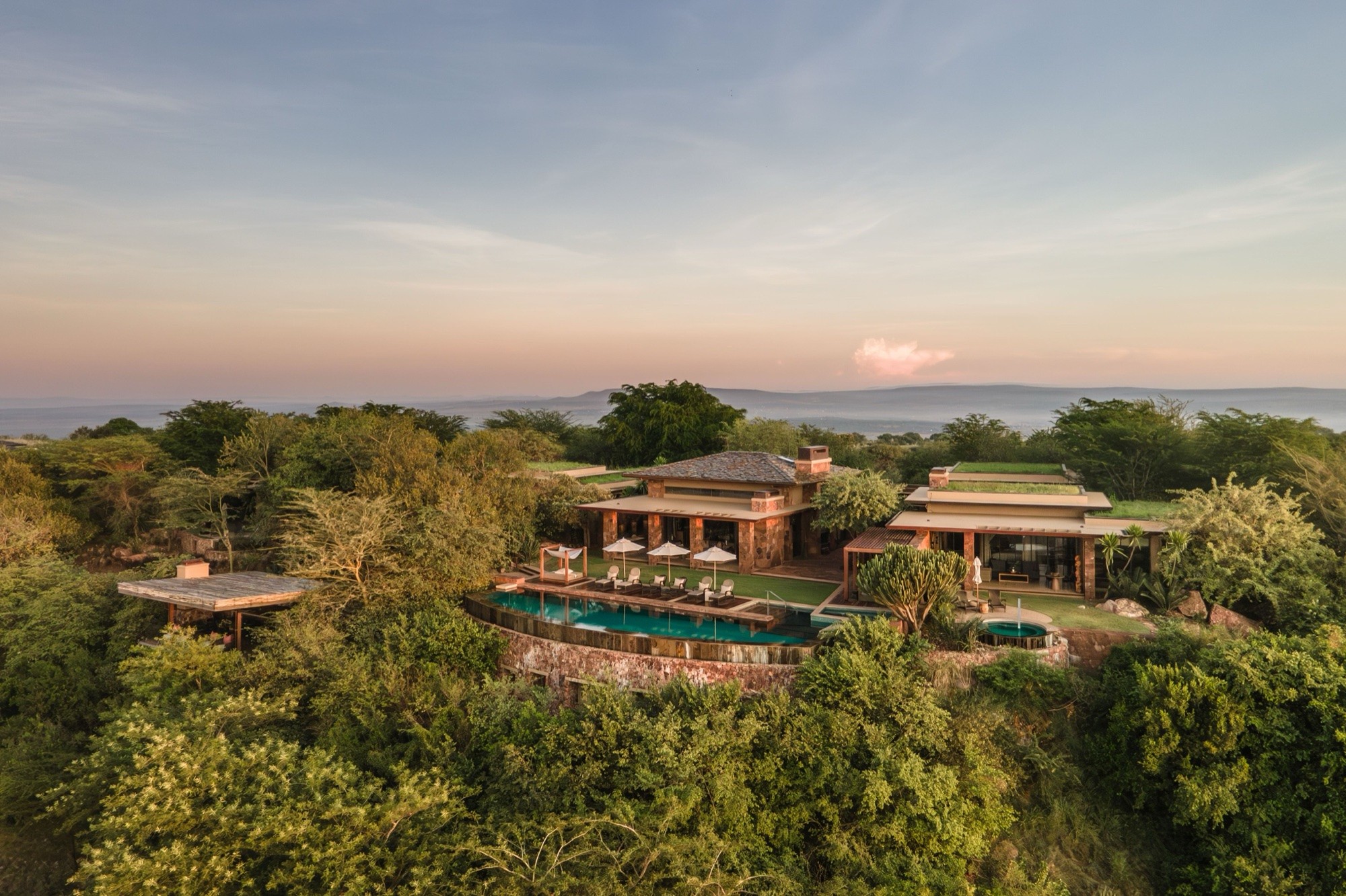 Aerial view of a hilltop lodge and infinity pool above the plains