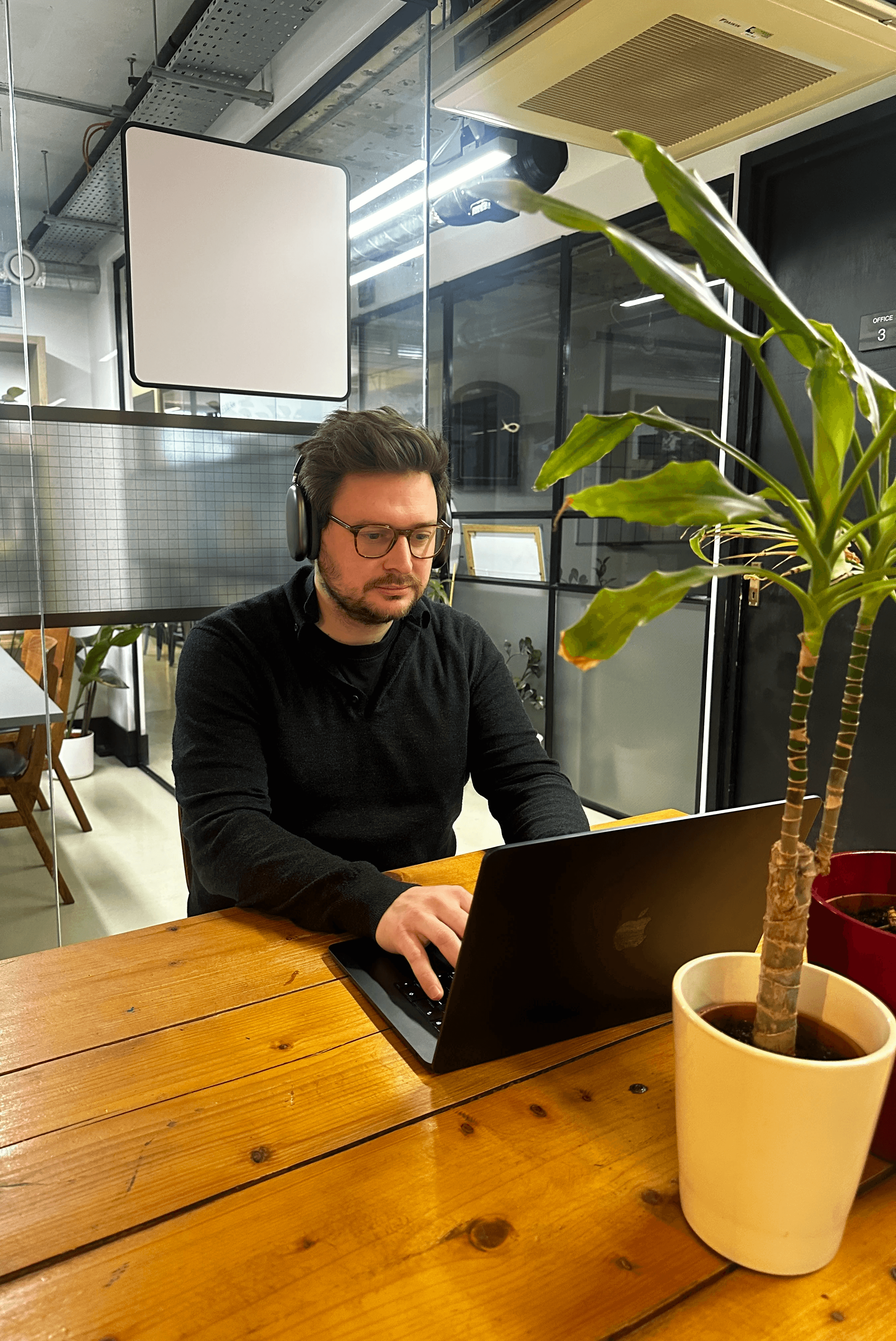 three men sitting while using laptops and watching man beside whiteboard