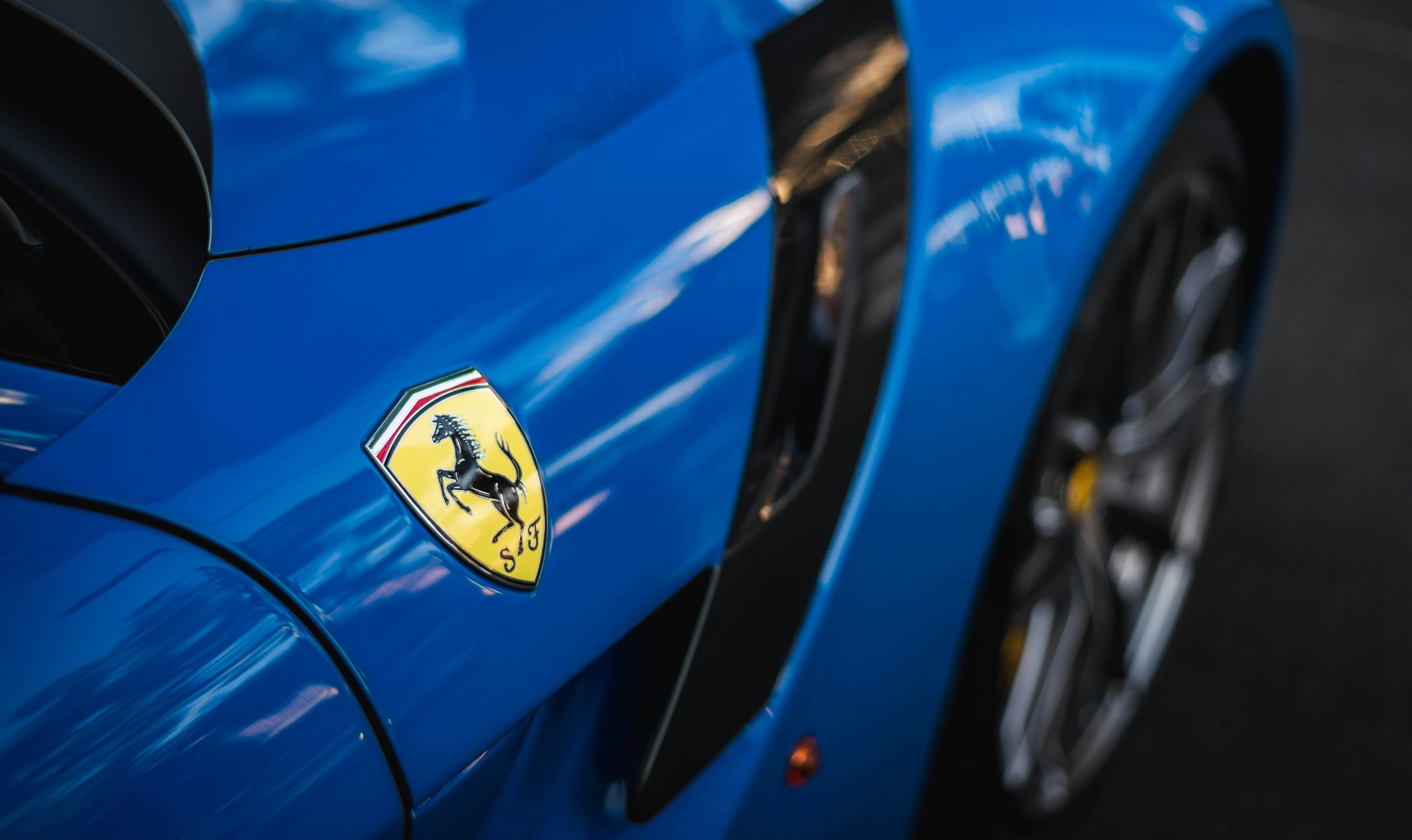 Logo Ferrari sur carrosserie bleue d’une Ferrari SF90 en gros plan