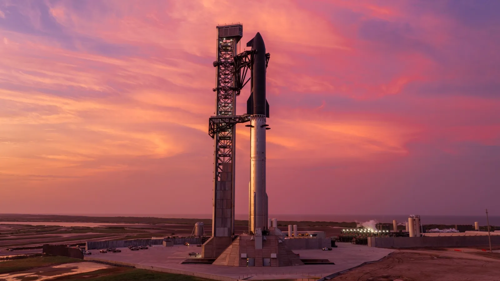 A sleek rocket stands vertically on a launchpad against a stunning sunset sky, with hues of pink and orange, highlighting the space exploration theme.