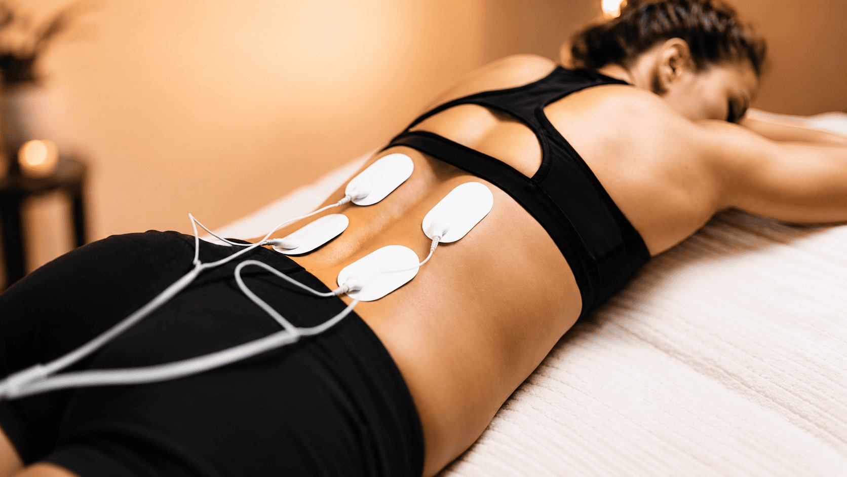 Woman undergoing electrotherapy therapy session as part of her rehabilitation program at Ember & Ice Health wellness center.