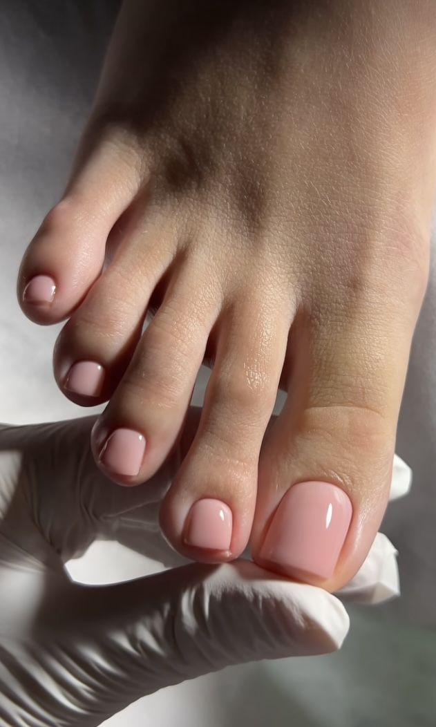 A woman lying down with a towel wrapped around her head, her face glistening with facial oil. Her eyes are closed, and she appears to be enjoying a spa treatment in a peaceful setting.