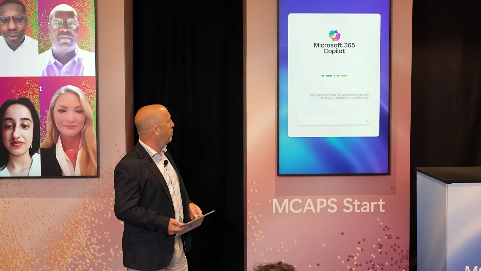 Presenter interacting with live digital content displayed on large on-stage screens during a corporate event.