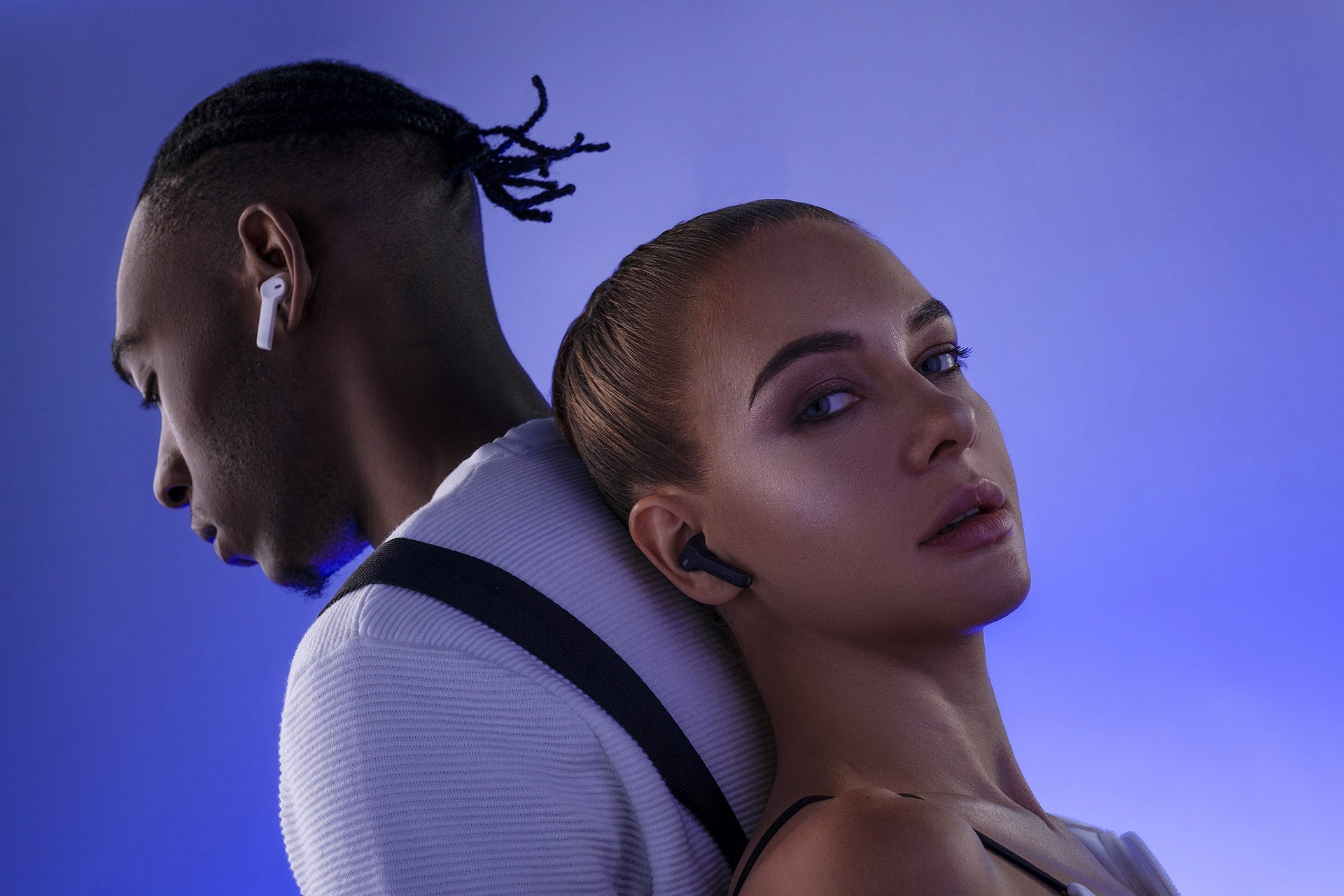 man and woman posing with earbuds in purple background