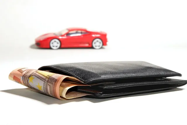 Wallet with Euros and red car in background
