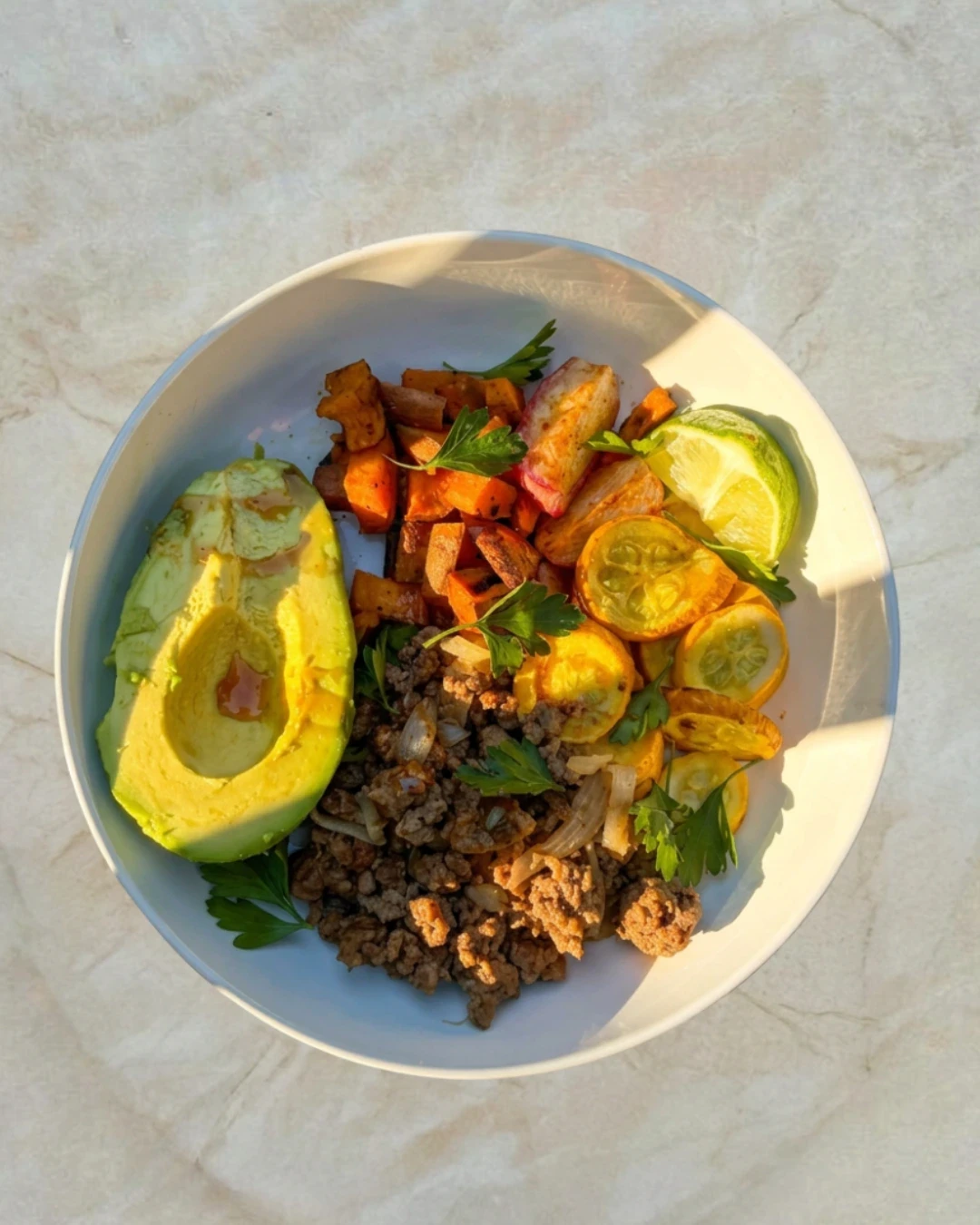 balanced beef bowl with avocado, honey, roasted zucchini and squash, fresh lime and parsley