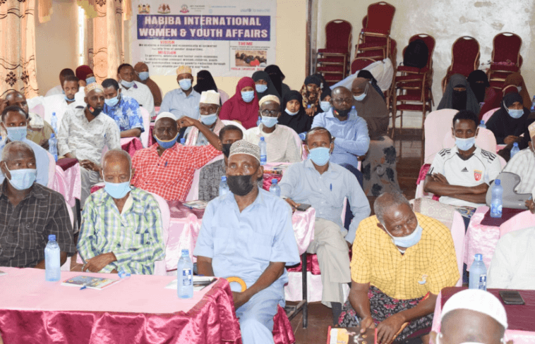 four boys laughing and sitting on grass during daytime