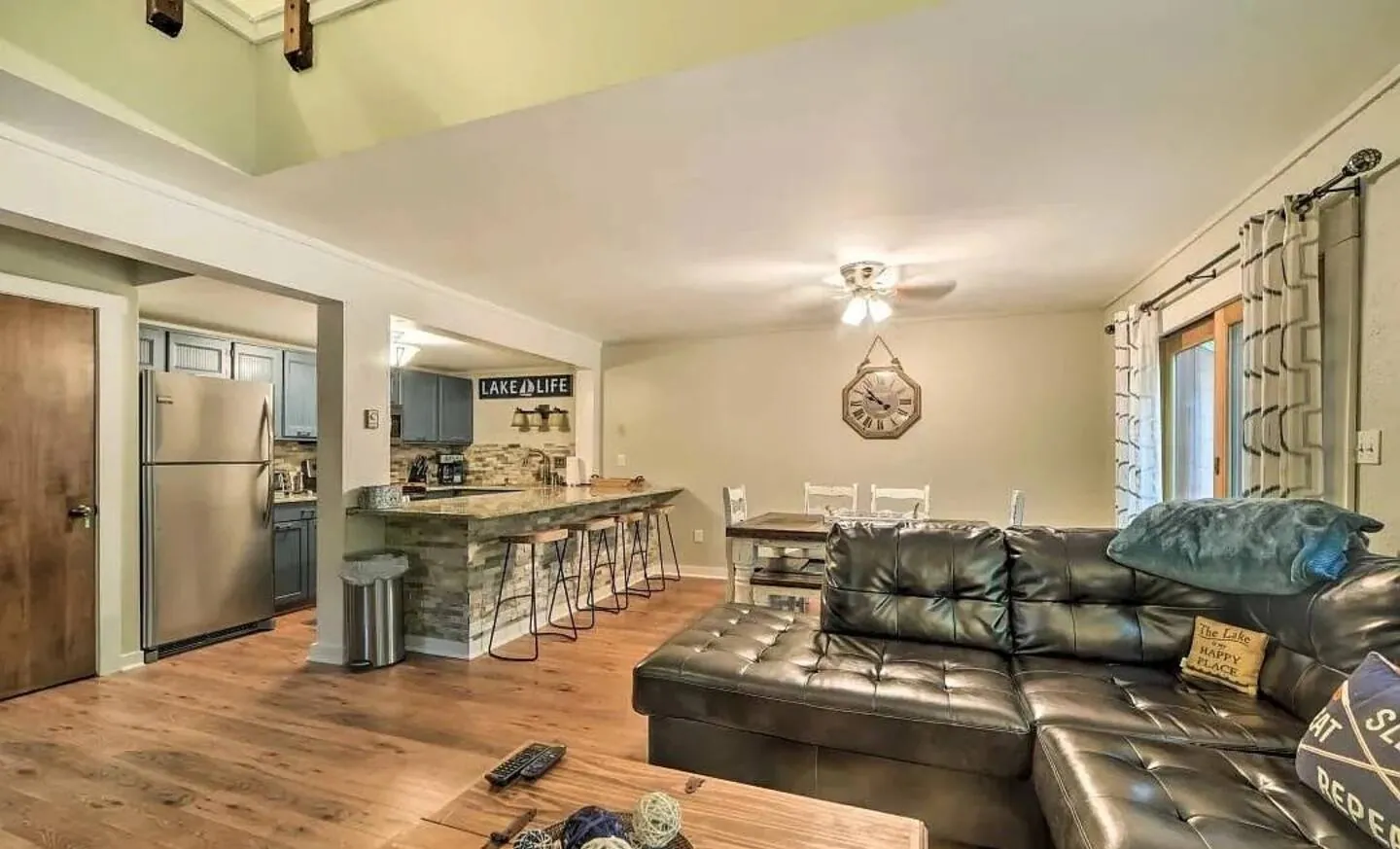 Open plan living room with black leather sectional and kitchen counter at Big Boulder Lake & Ski House