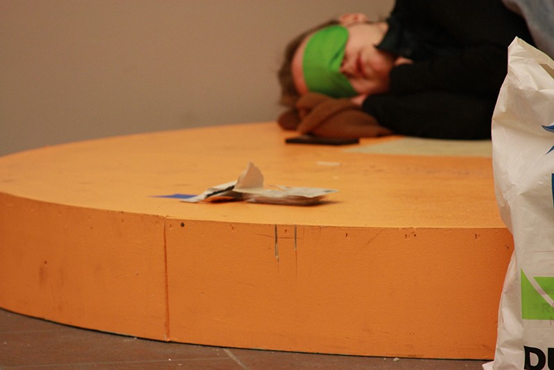 a person sleeping on a orange pedestal