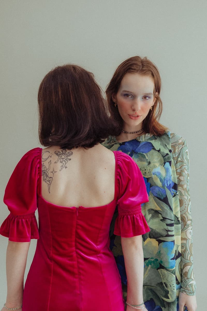 One model in a vibrant dress faces the camera while another model looks away, photographed at Revelator Studio, Shreveport’s premier natural light photography studio.