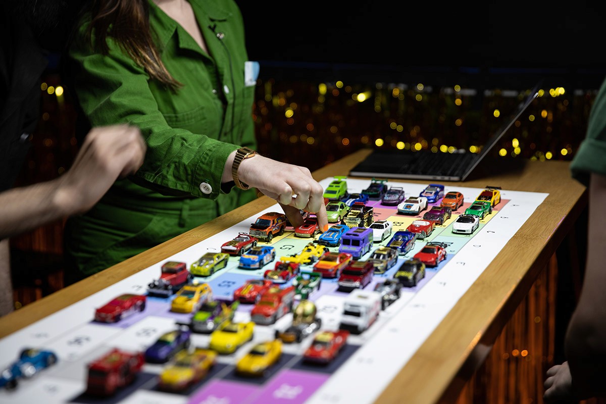 A performer touches a single car in a neatly laid formation of cars.