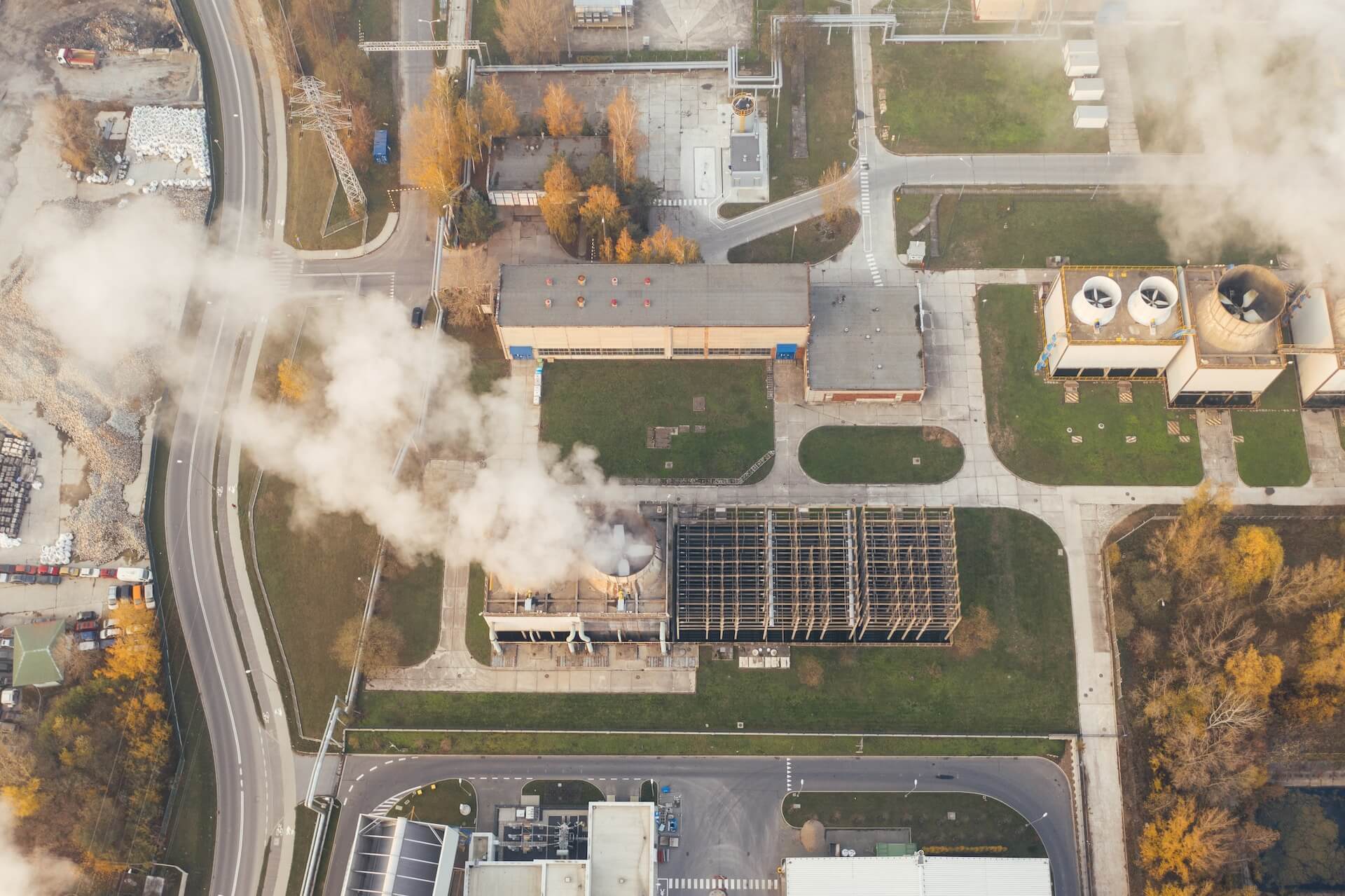 Overhead view of a townscape with prominent factory emitting smoke, illustrating industrial activity in the community.