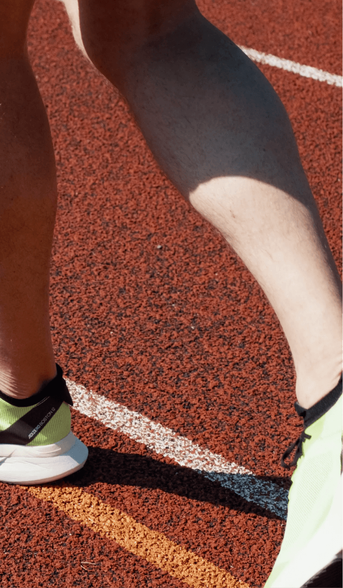 Closeup shot of a runner on a trackfield ready to start running wearing green shoes