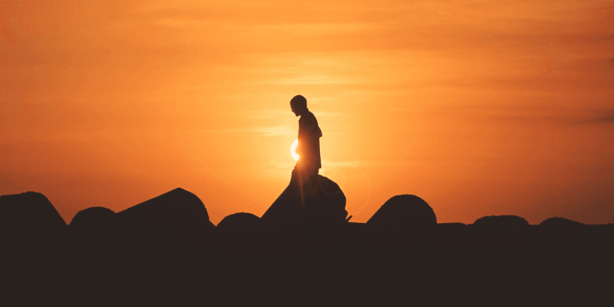 Silhouette of a lone figure walking over rocks at sunset, symbolizing Craig Logsdon’s transformative journey.