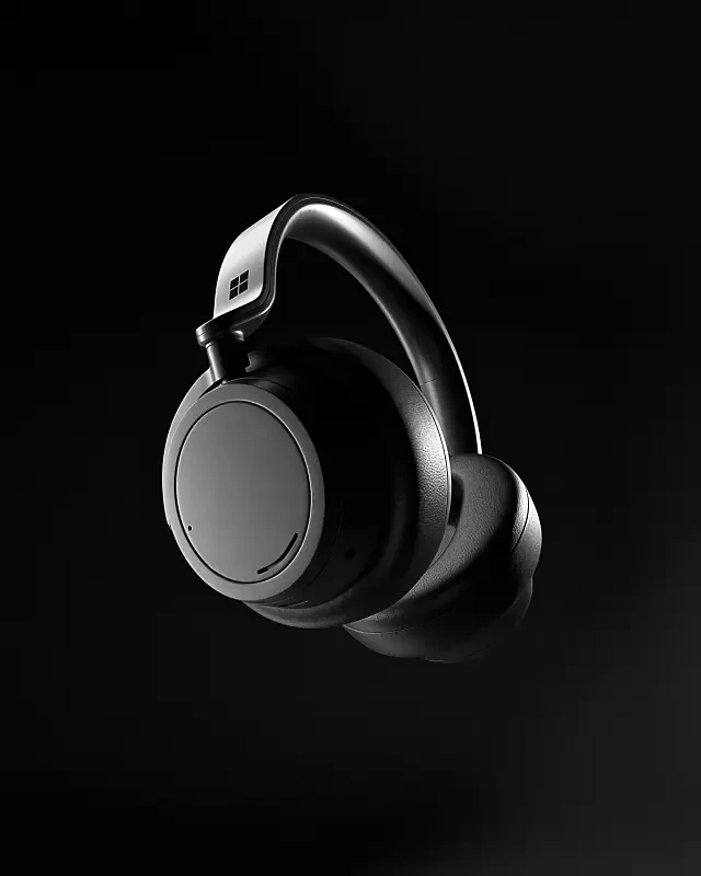A sleek, black over-ear headphone with cushioned ear pads and a minimalist design is suspended against a dark background, showcasing modern audio technology.