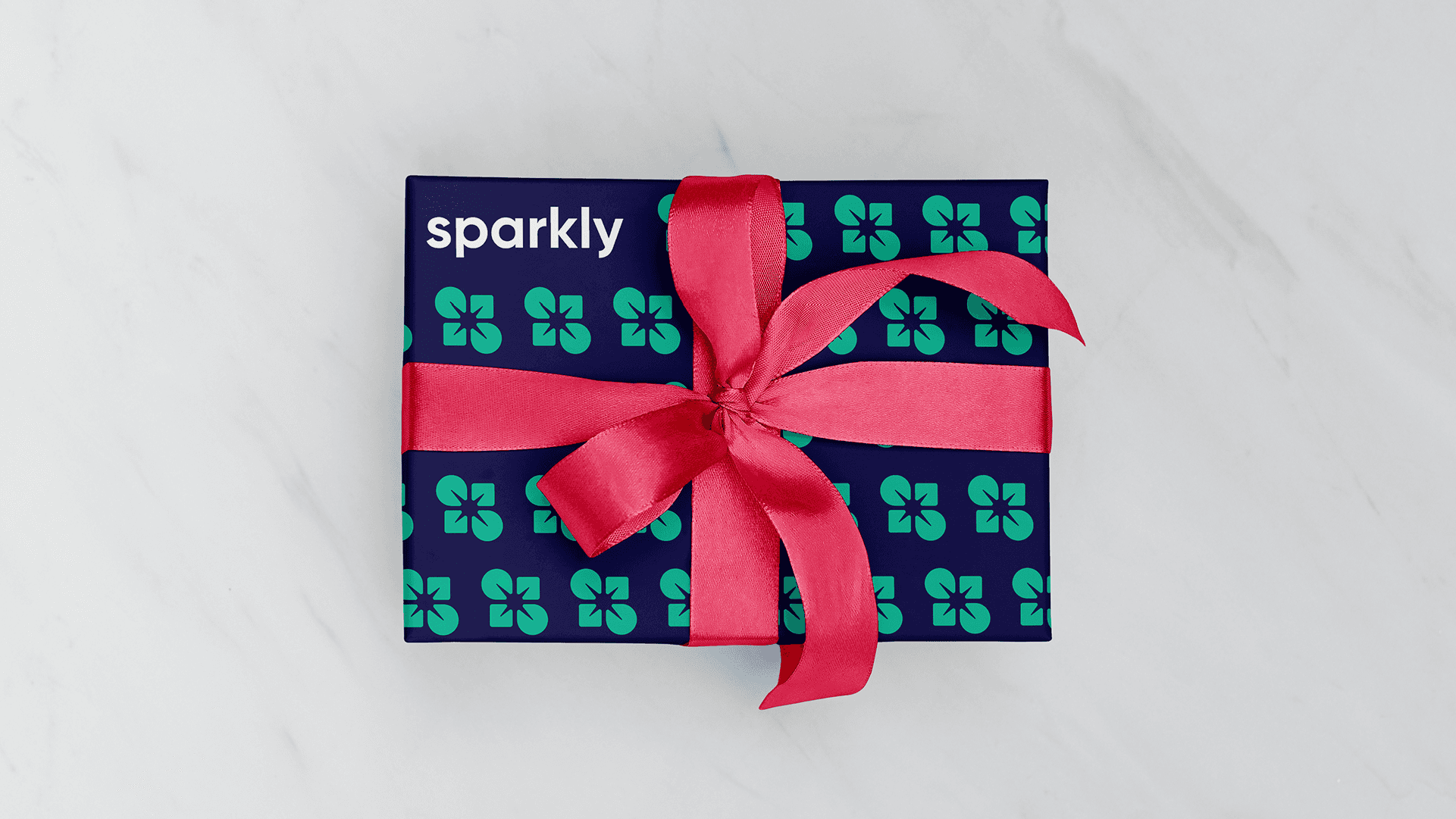 Gift box wrapped in navy Sparkly logo pattern paper with a red satin ribbon