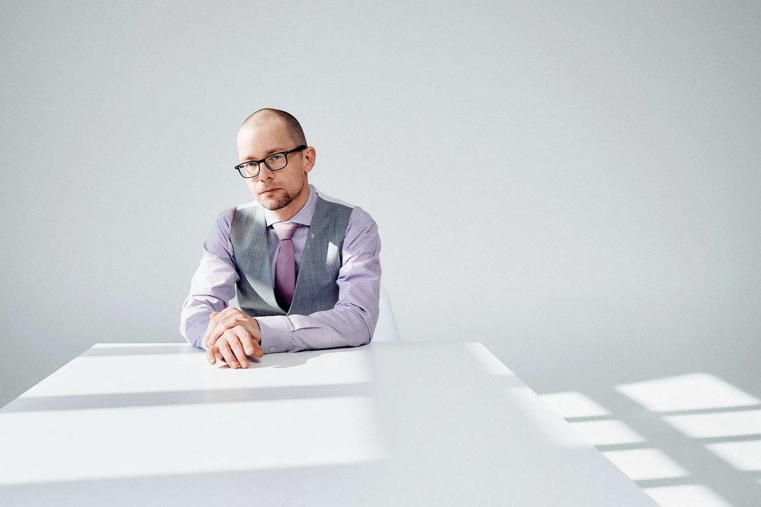 Business-Porträt von Frank Sonnabend an einem weißen Tisch, minimalistische Fotografie im Wytspace Mietstudio in Erfurt