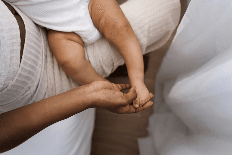 A person gently cradles a baby in a serene, intimate setting, emphasizing tender postpartum care, reflecting Ayurvedic postpartum practices in Louisville.