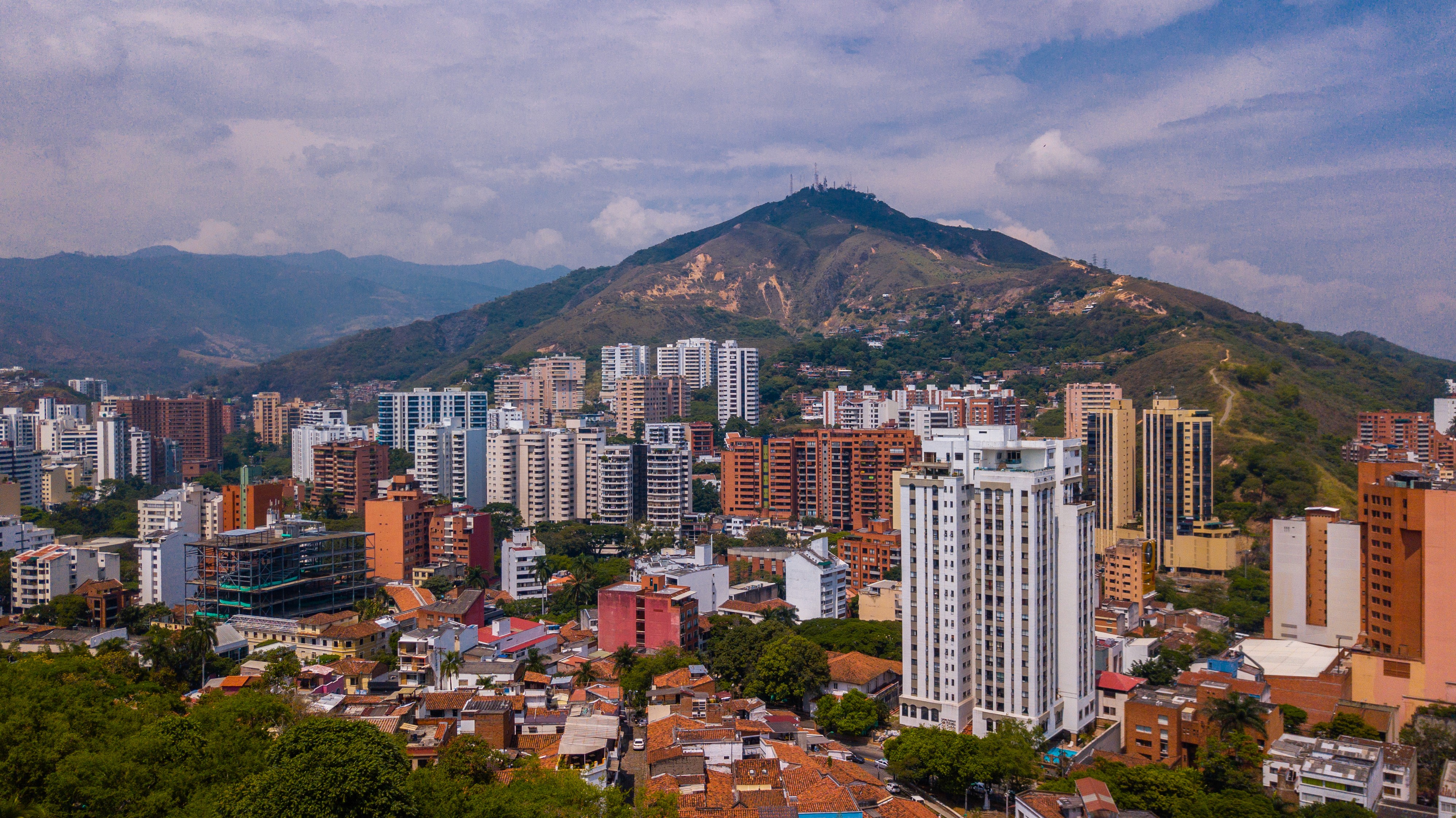 Woman in hat and boots squats in a green field.