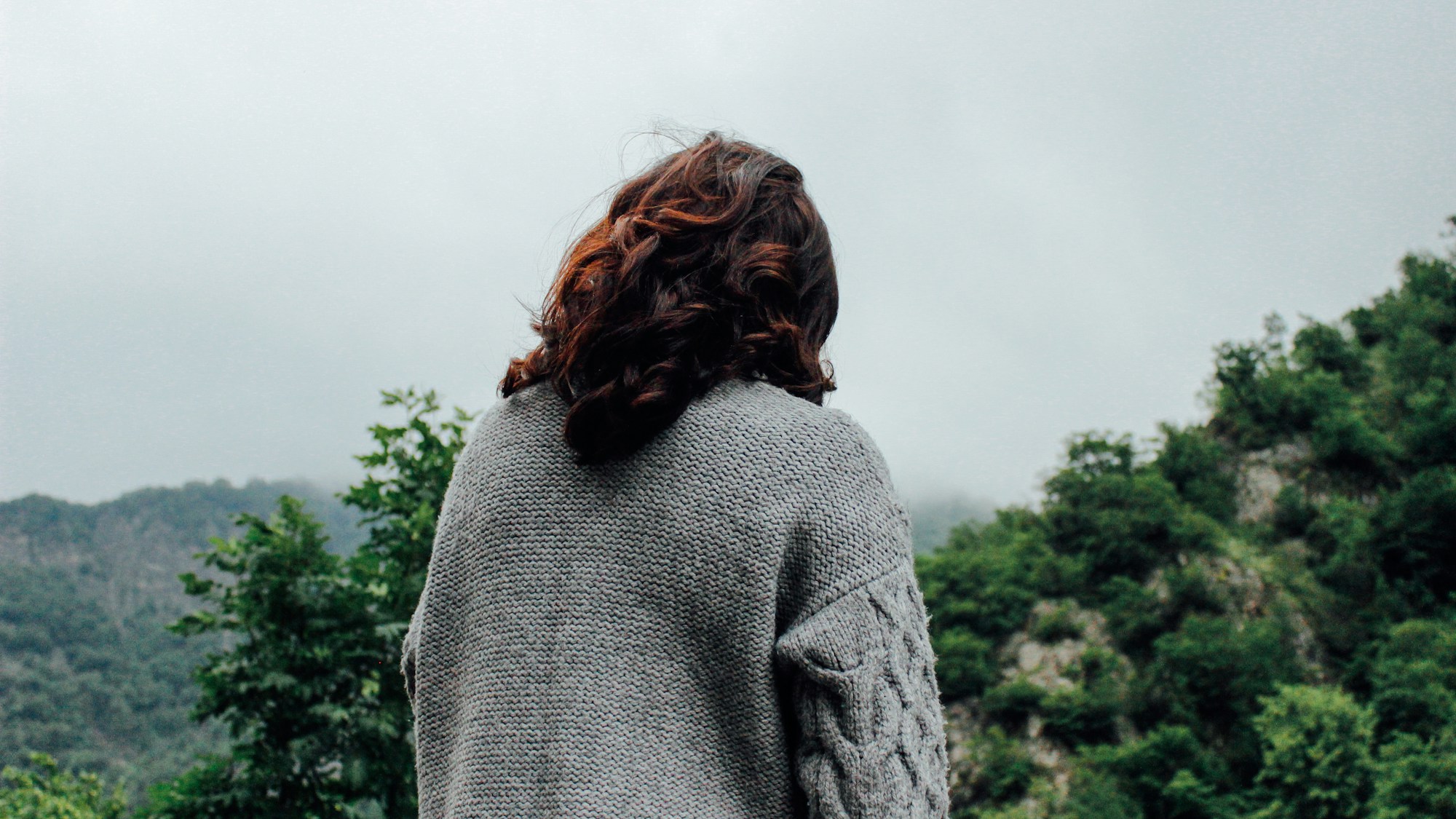 Model in a grey sweater in front of trees